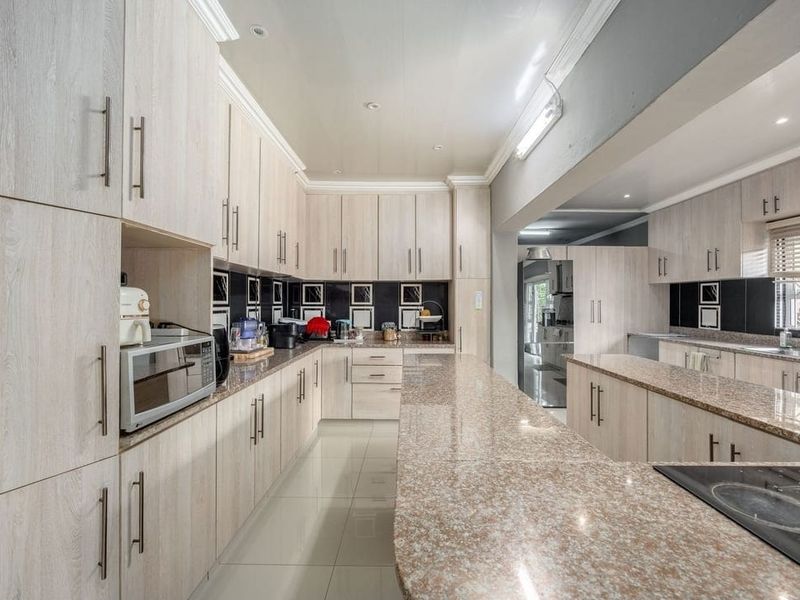 Spacious kitchen featuring extensive light wood-grain cabinetry, granite countertops, and tiled flooring, offering ample storage and workspace for culinary activities.