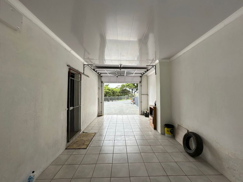 A clean, tiled garage space featuring a secure entrance gate and overhead door mechanism, providing functional vehicle storage or utility space.