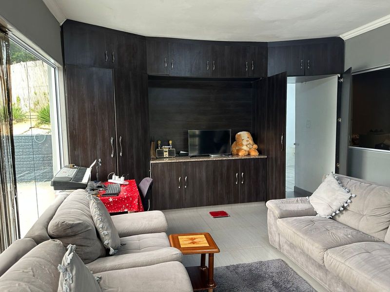 A living room featuring extensive dark wood built-in cabinetry with granite surfaces, tiled flooring, and large sliding glass doors providing natural light.