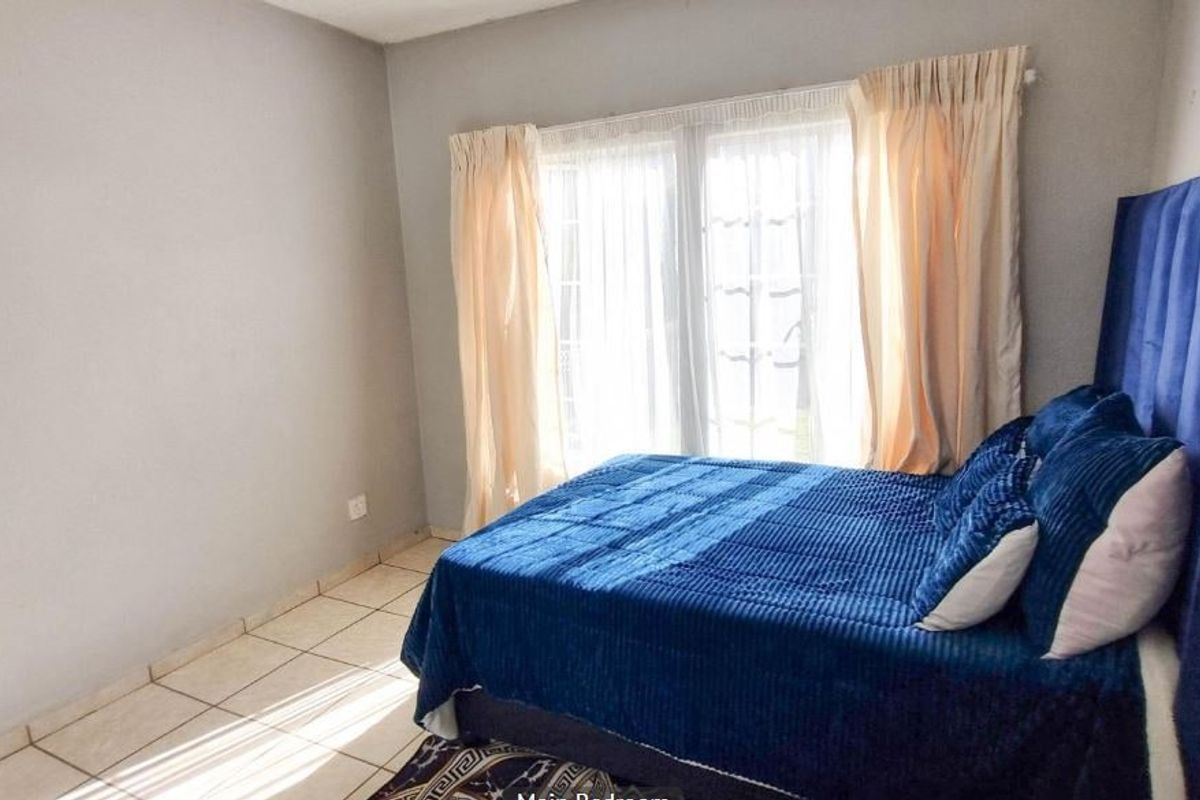 A bedroom featuring tiled flooring and a window with curtains, providing a functional and well-lit space.