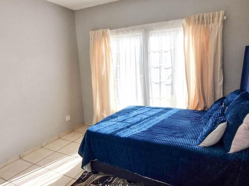 A bedroom featuring tiled flooring and a window with curtains, providing a functional and well-lit space.