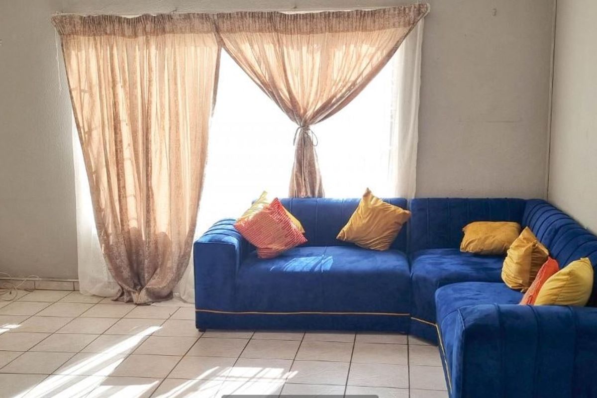 A living room area featuring ceramic tile flooring and a sliding glass door providing natural light.