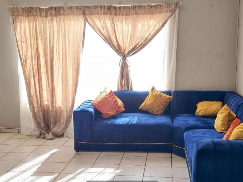 A living room area featuring ceramic tile flooring and a sliding glass door providing natural light.