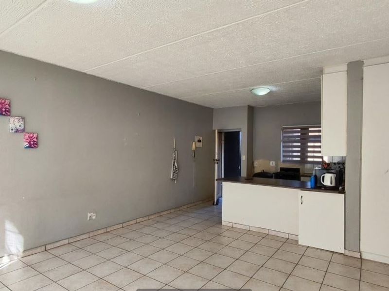 Open plan living area featuring tiled flooring, a breakfast counter, and built-in storage cupboards, offering a functional and versatile space.