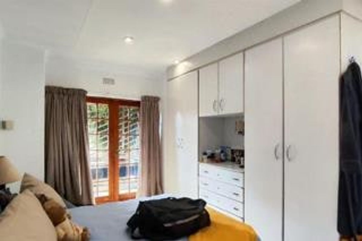 A well-lit bedroom featuring extensive built-in cabinetry with integrated vanity and direct access to the outdoors through wooden french doors.