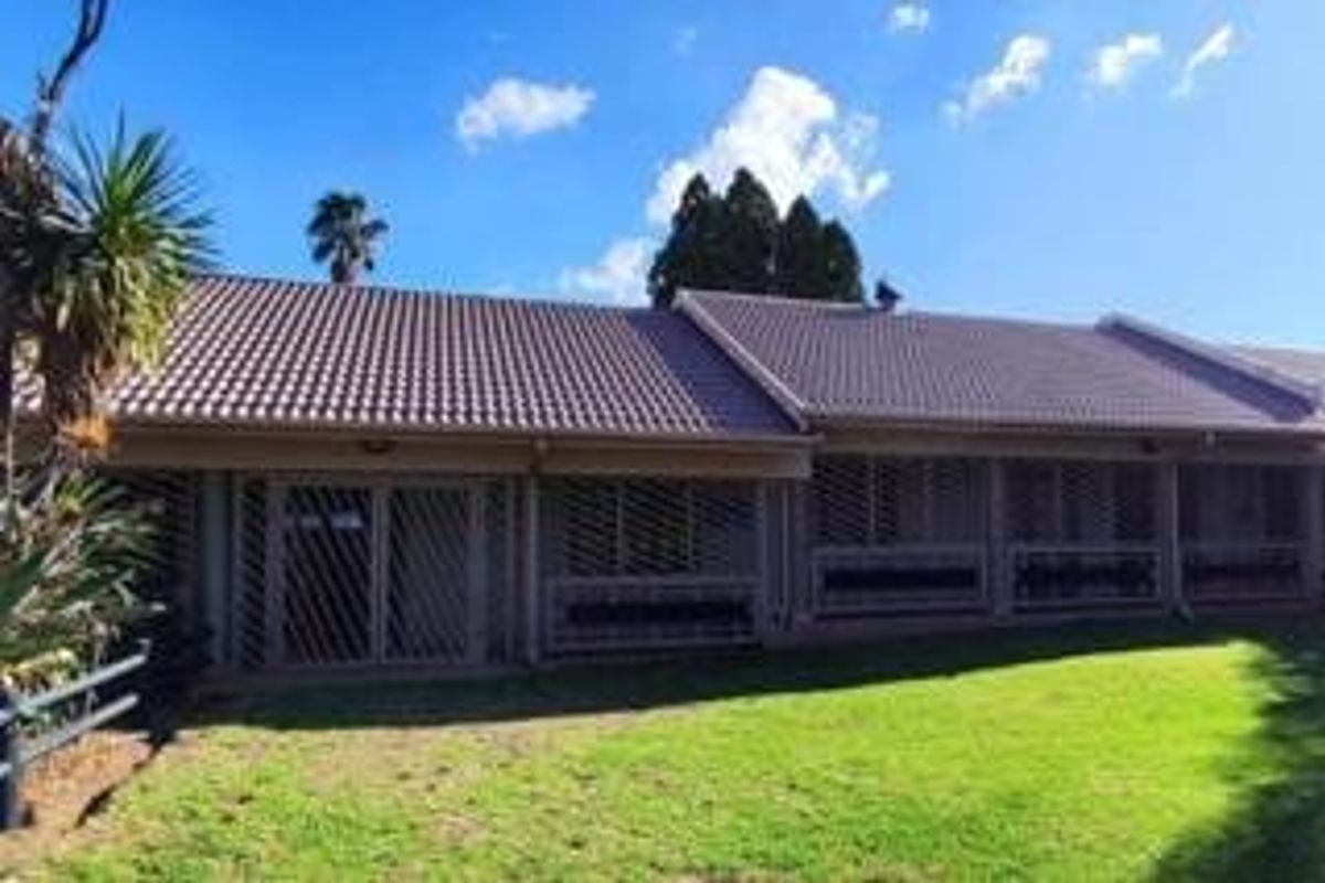 Rear view of the house featuring a tiled roof, security-fitted sliding doors, and a well-maintained lawn area.