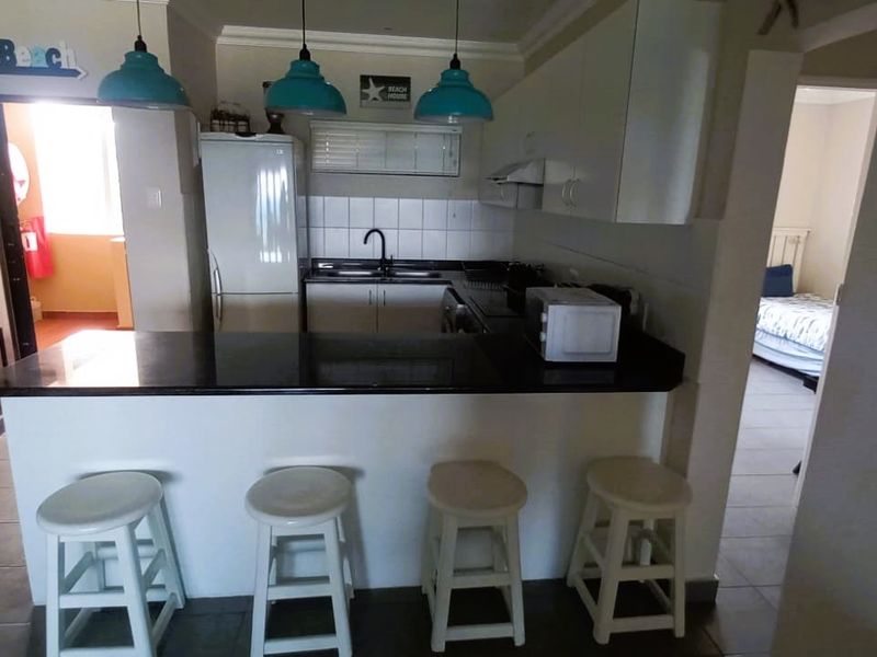 A functional kitchen featuring a breakfast bar, dark countertops, white cabinetry, and tiled flooring, providing a practical layout for daily meal preparation.