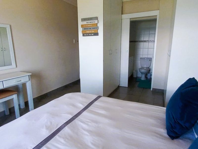 Bedroom featuring built-in cupboards and an adjoining en-suite bathroom with tiled flooring throughout.