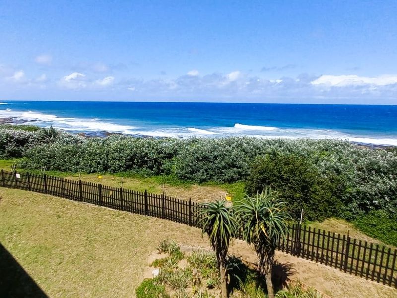 An elevated coastal view overlooking the ocean, beach, and surrounding natural landscape with perimeter fencing visible.