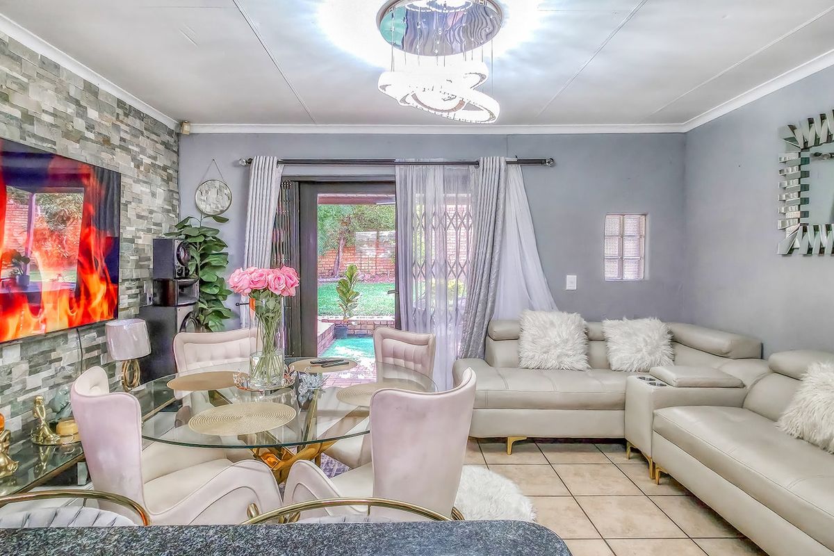 A well-lit living area featuring a stone veneer accent wall, tiled flooring, and direct access to the rear garden through a sliding glass door.