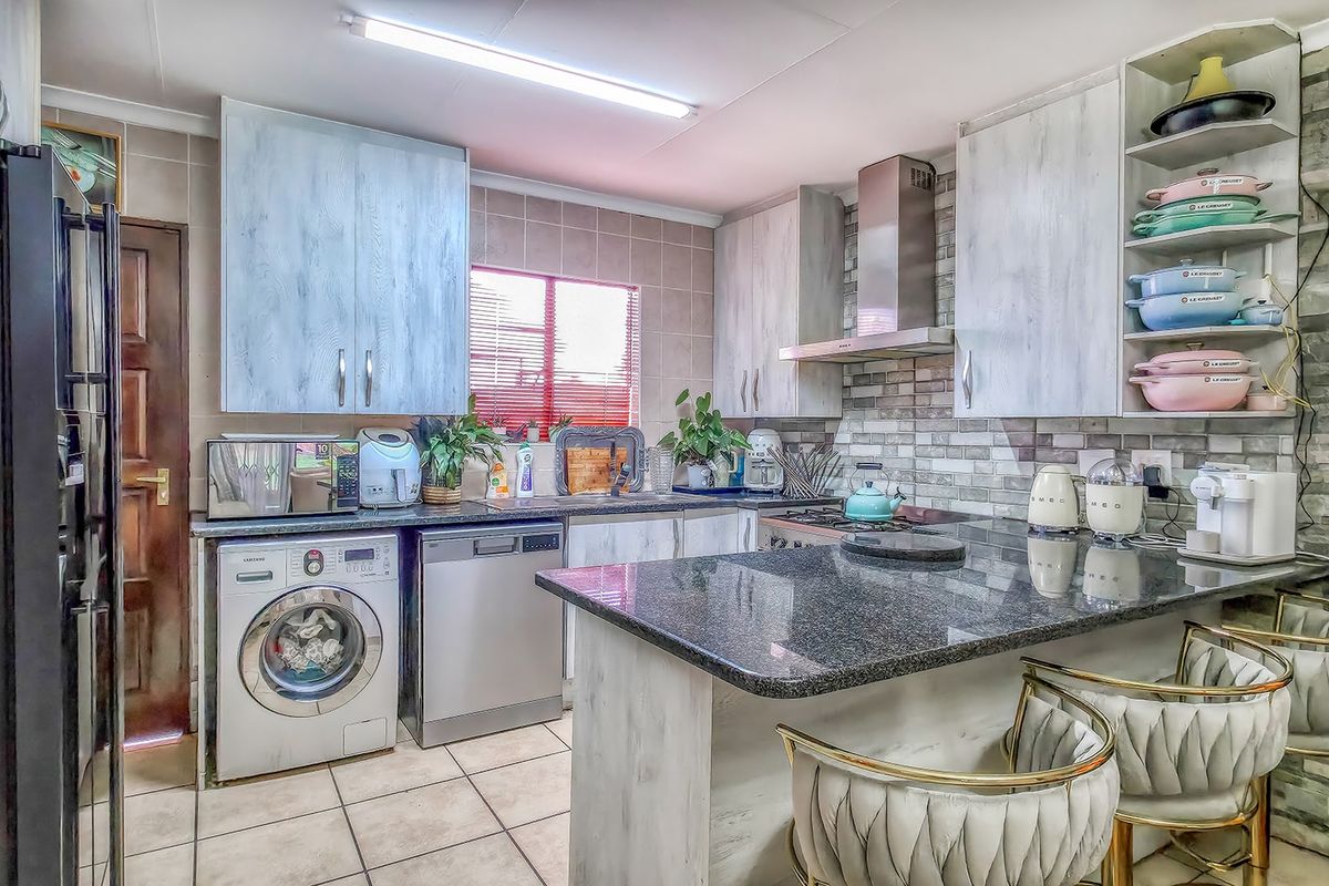 A functional kitchen featuring granite countertops, stone veneer accents, built-in cabinetry, and integrated appliance spaces, offering a practical layout for daily use.