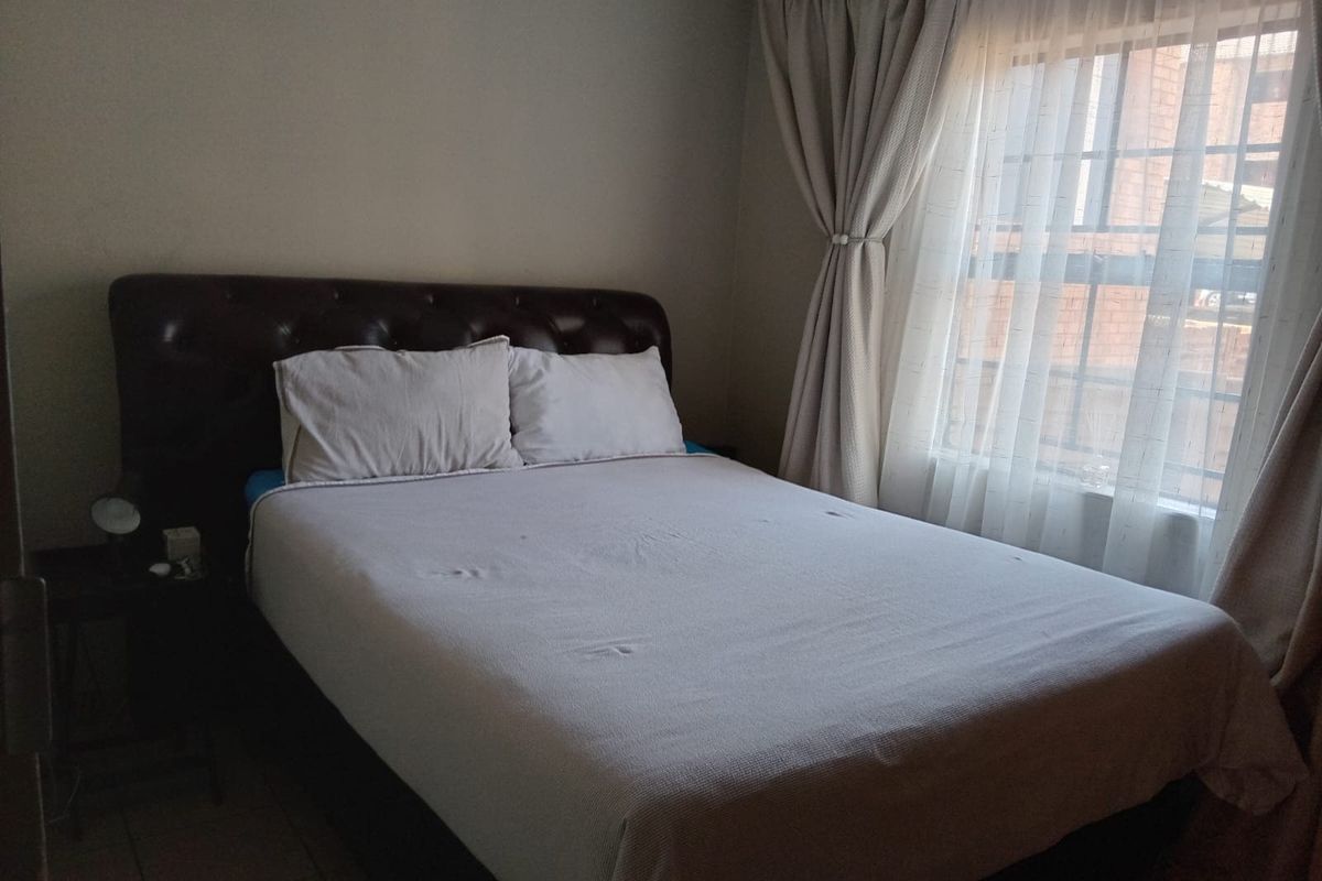 A standard bedroom featuring tiled flooring and a window with fitted curtain tracks.