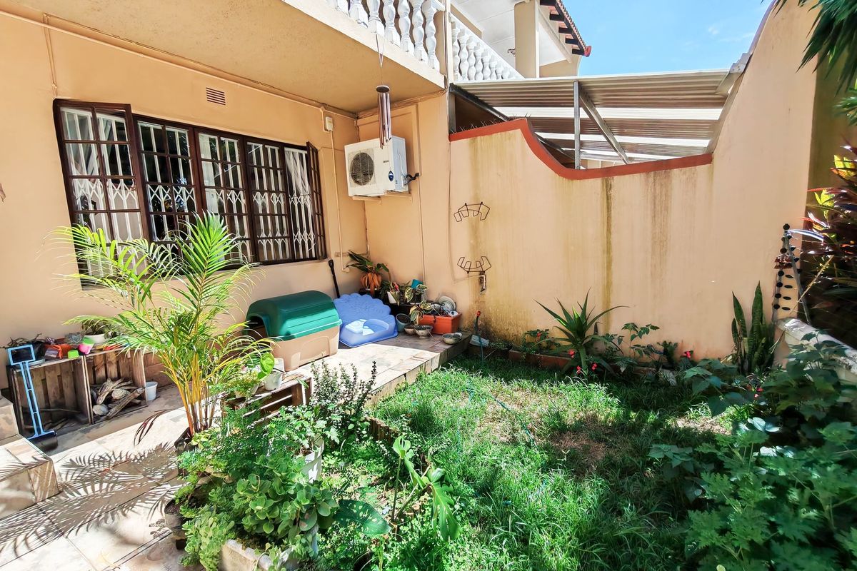 A rear courtyard area featuring a tiled patio, small garden space, and boundary wall, providing a private outdoor area for the apartment.