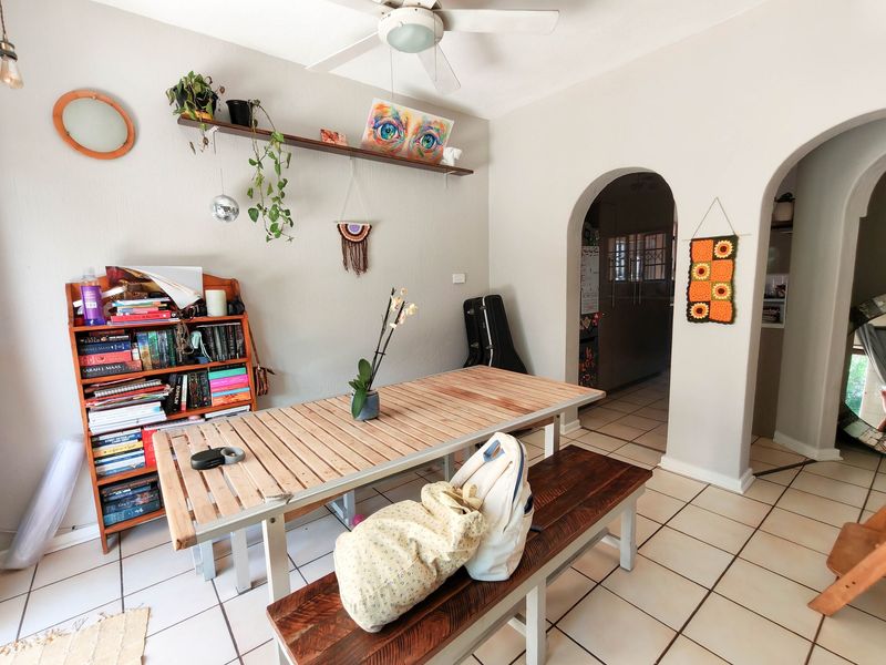 Dining area featuring tiled flooring, a ceiling fan, and distinctive architectural archways leading to adjacent spaces.