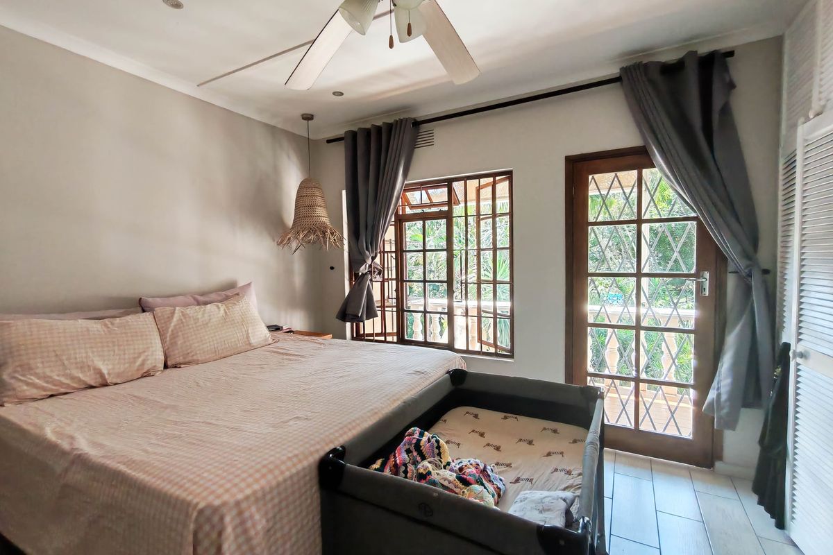 A bedroom featuring tiled flooring, a ceiling fan, and direct access to an outdoor area through a wooden door with security bars.