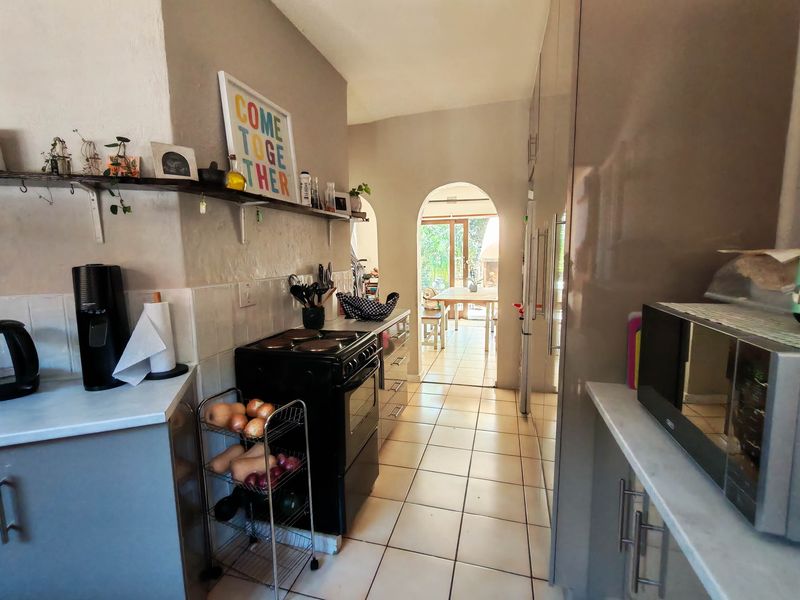 A functional kitchen featuring tiled flooring, built-in cabinetry, and a classic archway leading to an adjacent dining area.