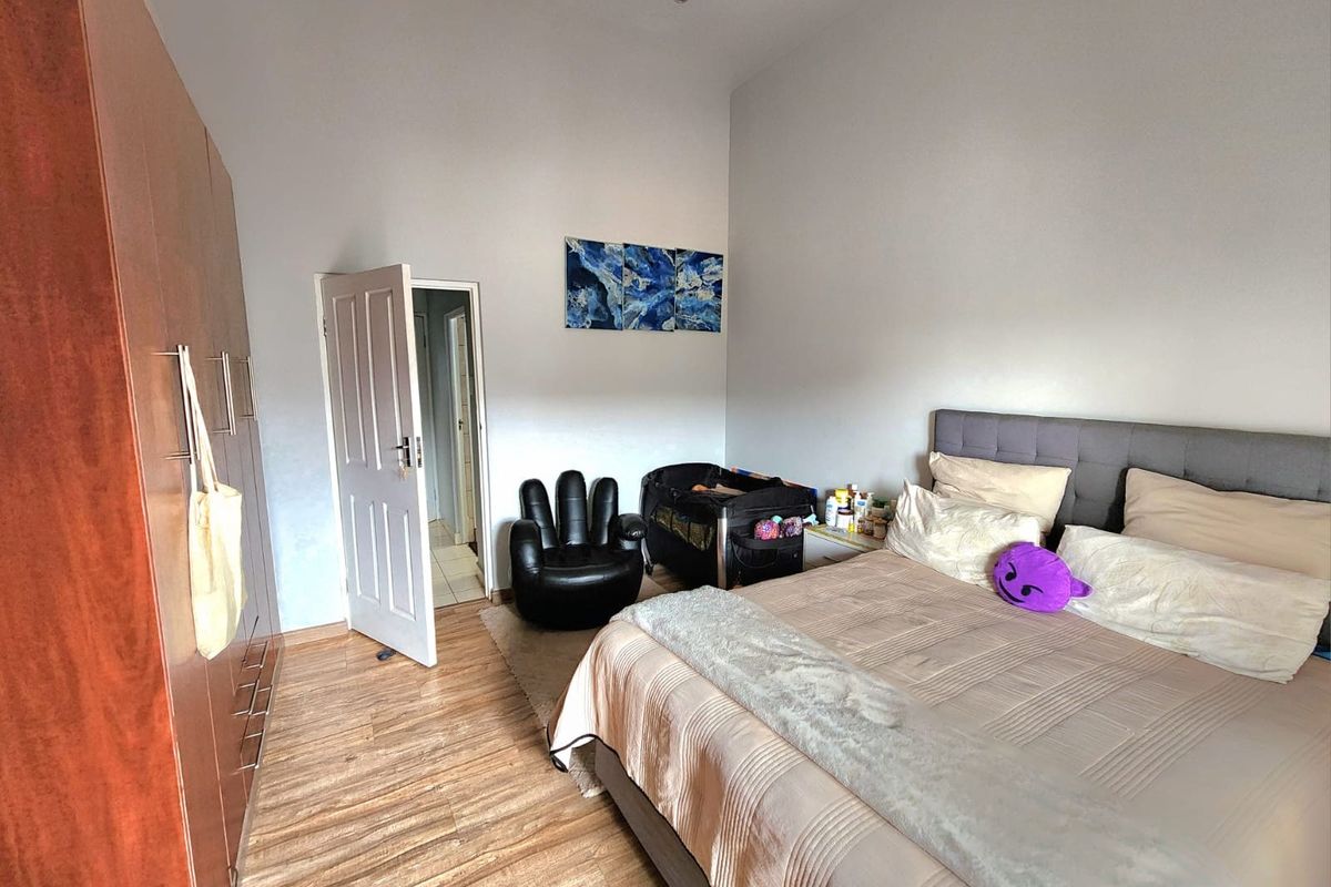 A well-maintained bedroom featuring laminate flooring, built-in wardrobes, and recessed lighting, offering a comfortable and functional living space.