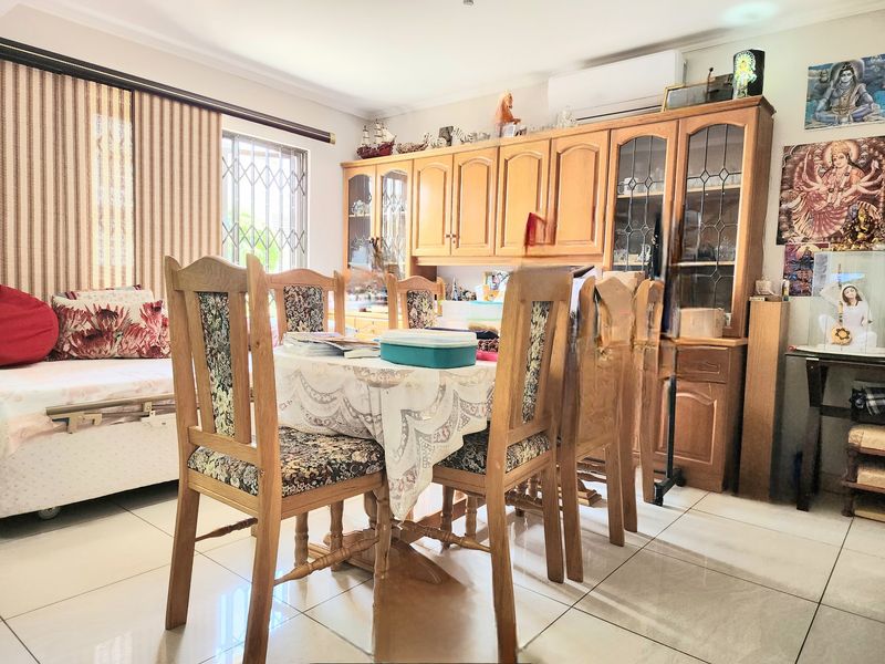 A dining area featuring tiled flooring, a large built-in wooden wall unit, and an air conditioning unit, providing a functional space for meals.