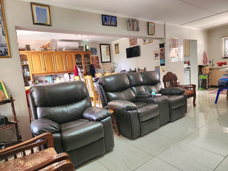 Spacious open-plan living area featuring tiled flooring, built-in cabinetry, and an integrated kitchen space with neutral finishes.
