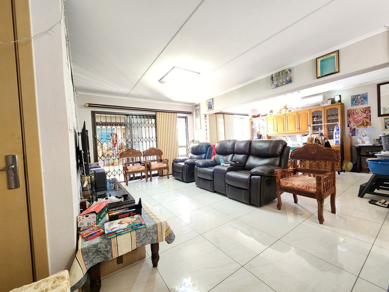 Spacious open-plan living area featuring large floor tiles, built-in cabinetry, and a security gate leading to the exterior.