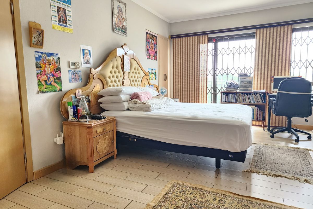A spacious bedroom featuring tiled flooring, built-in cupboards, and a security gate leading to an outdoor area.