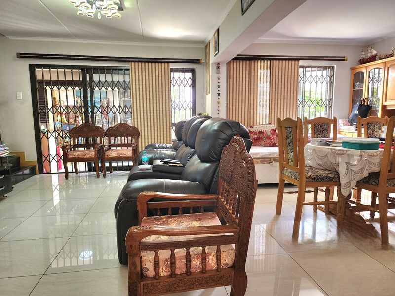 Spacious open-plan living and dining area featuring polished porcelain floor tiles, large sliding doors with security gates, and integrated lighting.