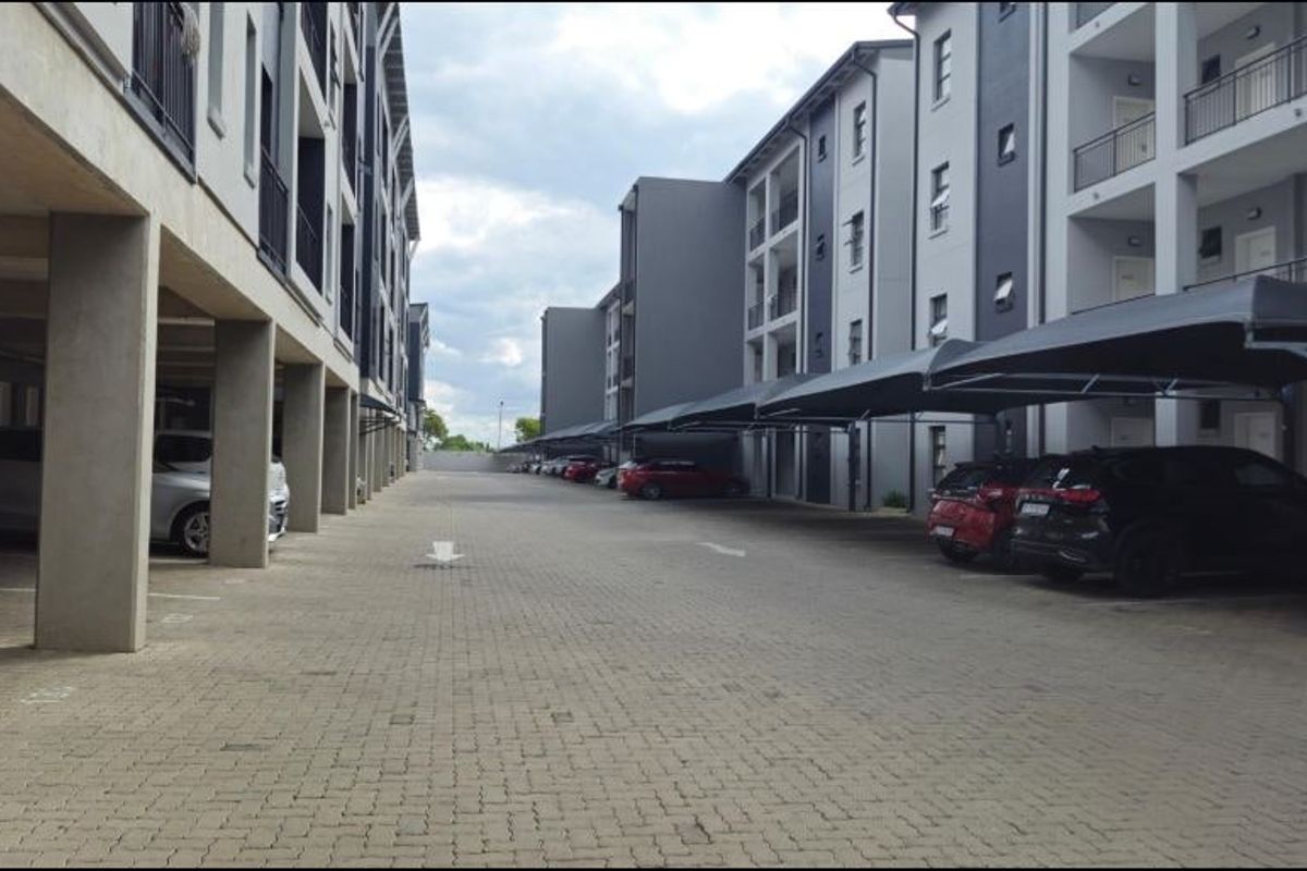 Exterior view of the apartment complex parking area featuring paved driveways and covered parking bays for residents.