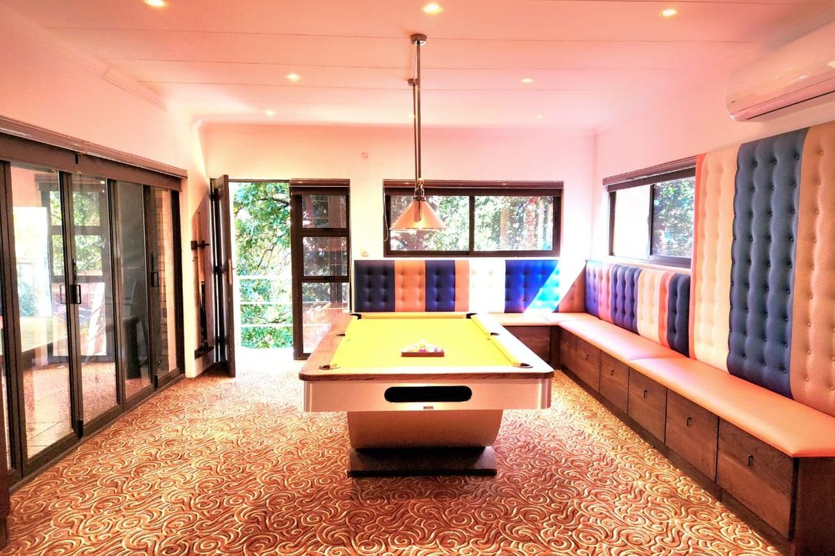 Spacious entertainment room featuring built-in bench seating, recessed lighting, and large sliding glass doors providing access to the outdoors.