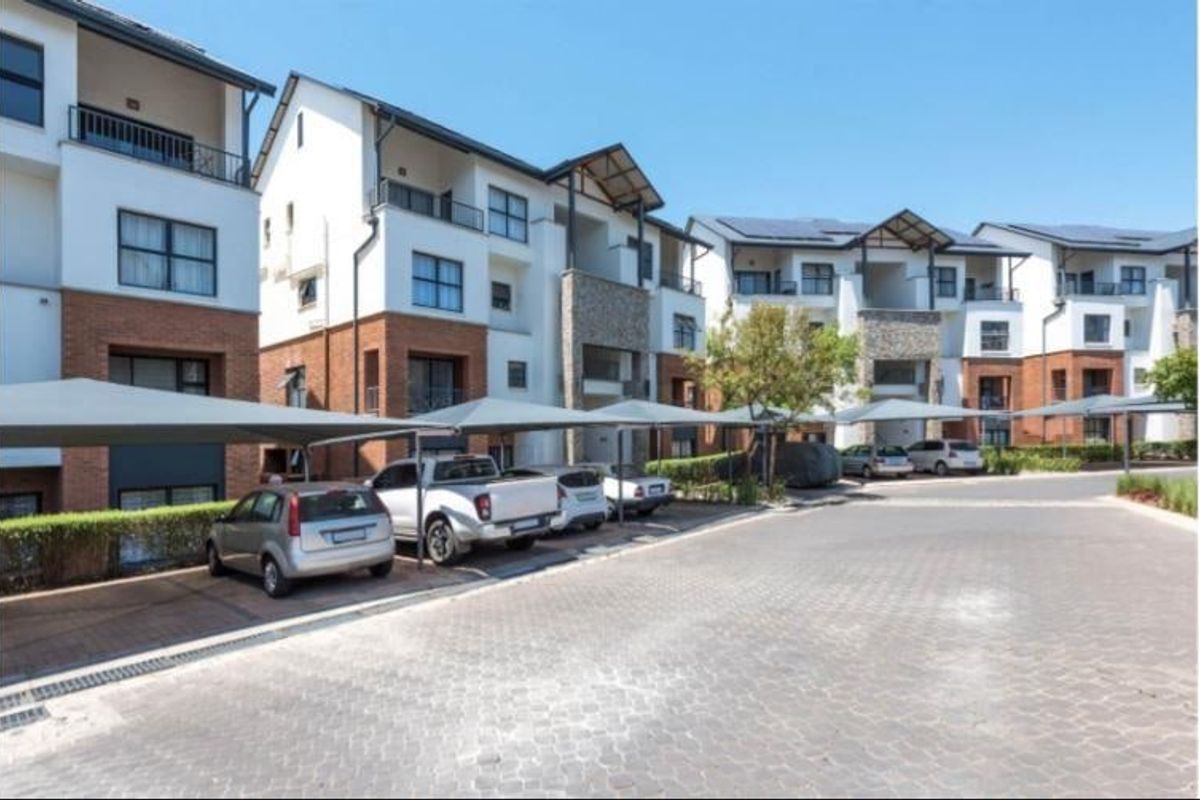 Exterior view of a modern apartment complex featuring brick and plaster facades, private balconies, and dedicated covered parking bays for residents.