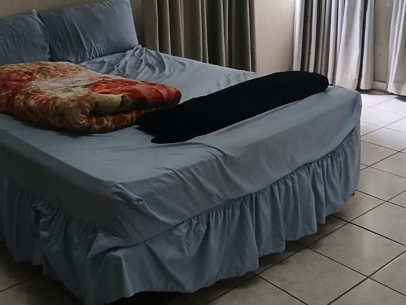 A bedroom featuring ceramic floor tiles and windows fitted with security bars, requiring cosmetic updates to improve the overall aesthetic.