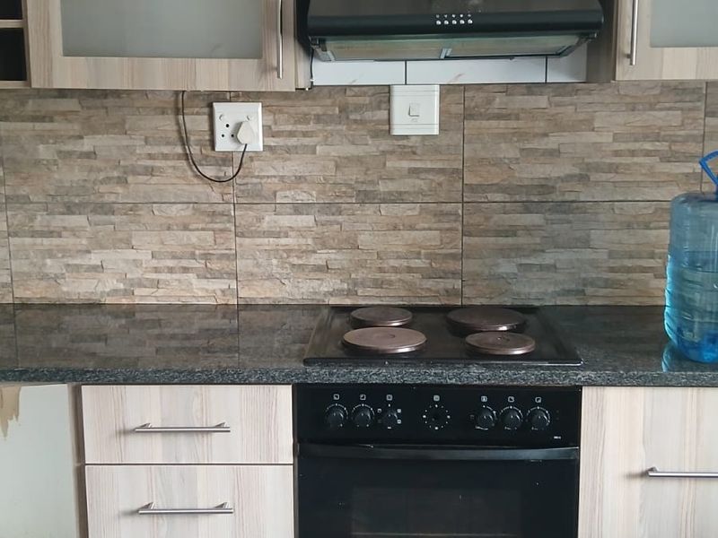 Kitchen featuring wood-look cabinetry, granite countertops, and built-in oven with hob. Note the missing cabinet door and damaged base unit.