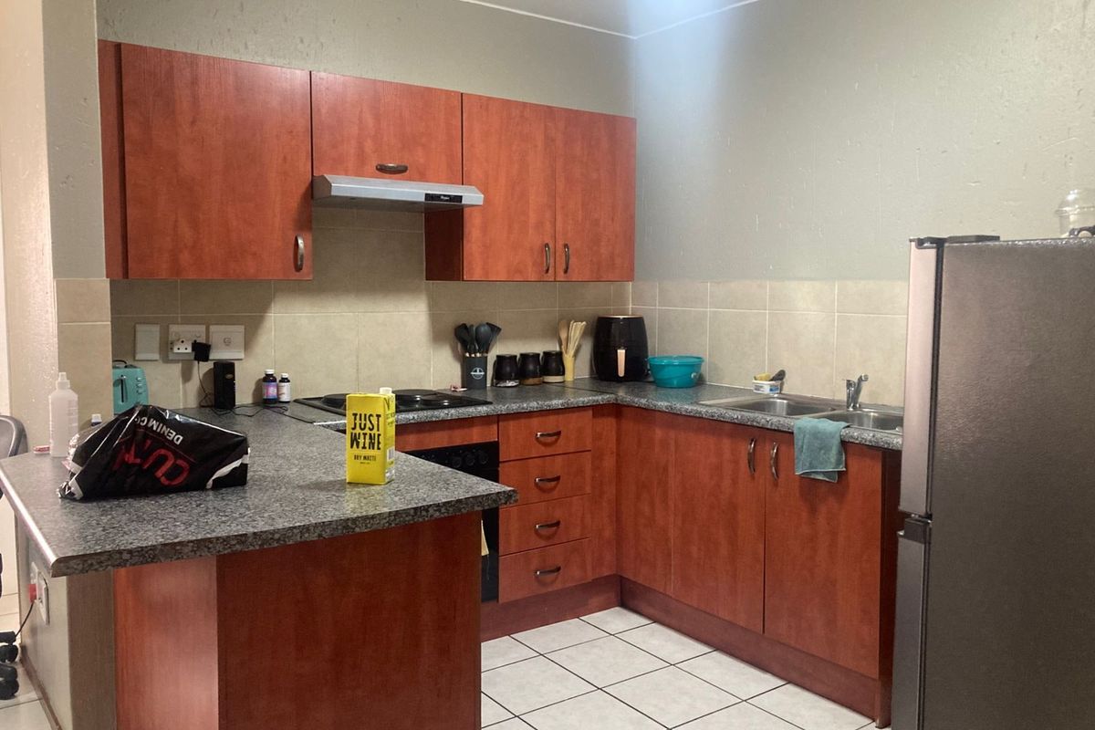 Functional kitchen featuring wood-look cabinetry, granite-style countertops, tiled backsplash, and built-in cooking appliances with a breakfast bar peninsula.