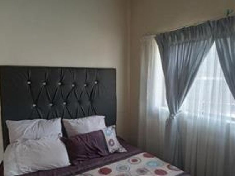 A standard bedroom featuring neutral wall finishes and window treatments.
