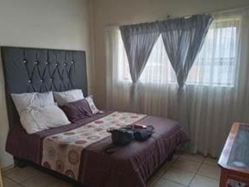 A standard bedroom featuring tiled flooring and window treatments, providing a functional space for rest.