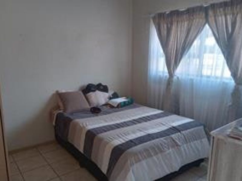 A standard bedroom featuring tiled flooring and window curtain rails, providing a functional space for rest.
