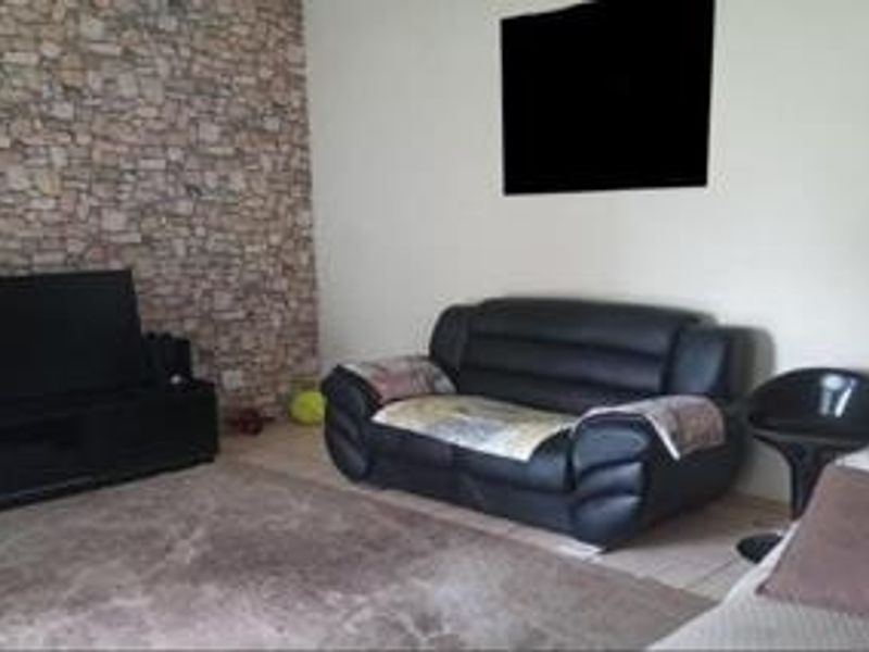 A living room featuring a stone veneer accent wall and tiled flooring, providing a neutral base for interior design updates.