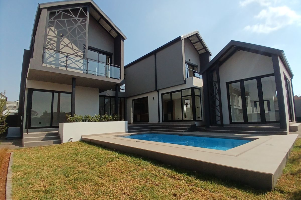 Modern architectural rear elevation featuring a swimming pool, expansive glass sliding doors, and contemporary metal detailing on a multi-level structure.