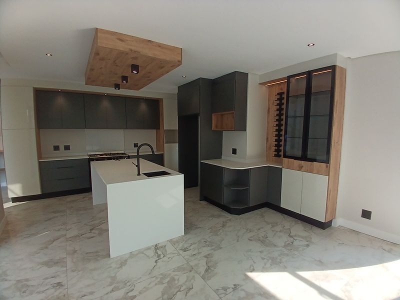 Modern kitchen featuring a central island, sleek two-tone cabinetry, integrated wine storage, and high-quality marble-look floor tiles.