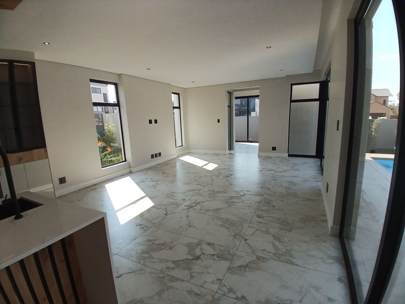 Spacious open-plan living area featuring modern marble-look floor tiles, recessed lighting, and large sliding glass doors providing seamless access to the outdoor pool area.