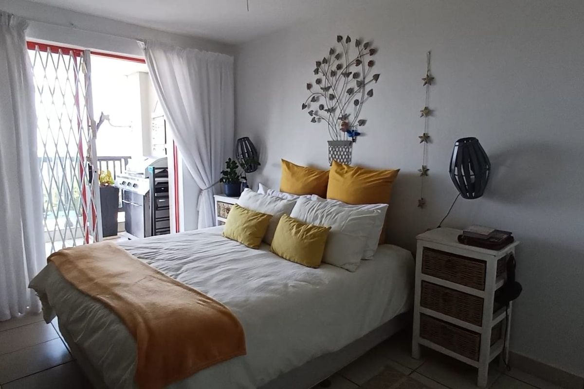 A well-lit bedroom featuring tiled flooring and a sliding glass door that provides access to an outdoor balcony area.