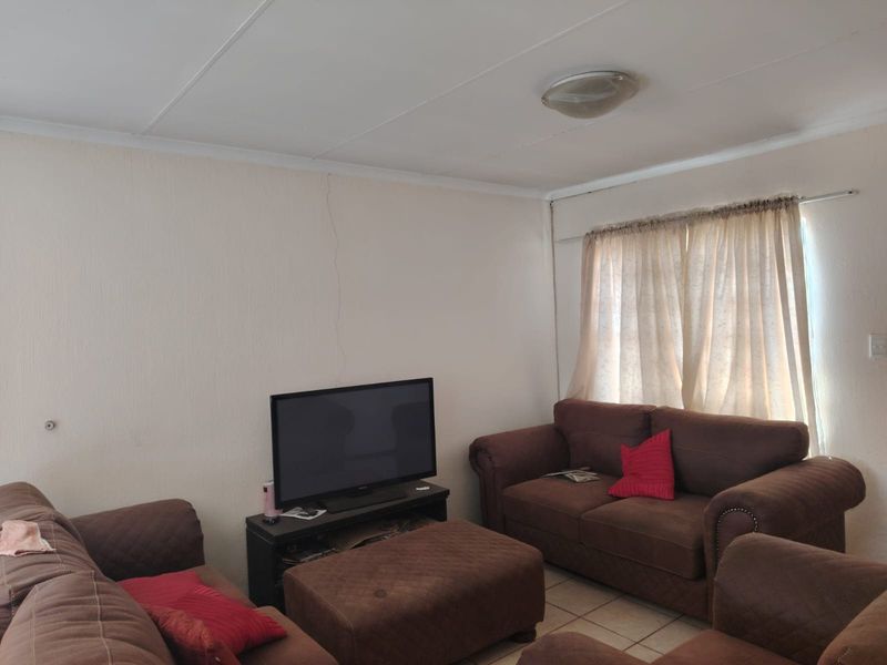 A living room featuring tiled flooring and a visible vertical wall crack, offering a functional space ready for cosmetic updates.