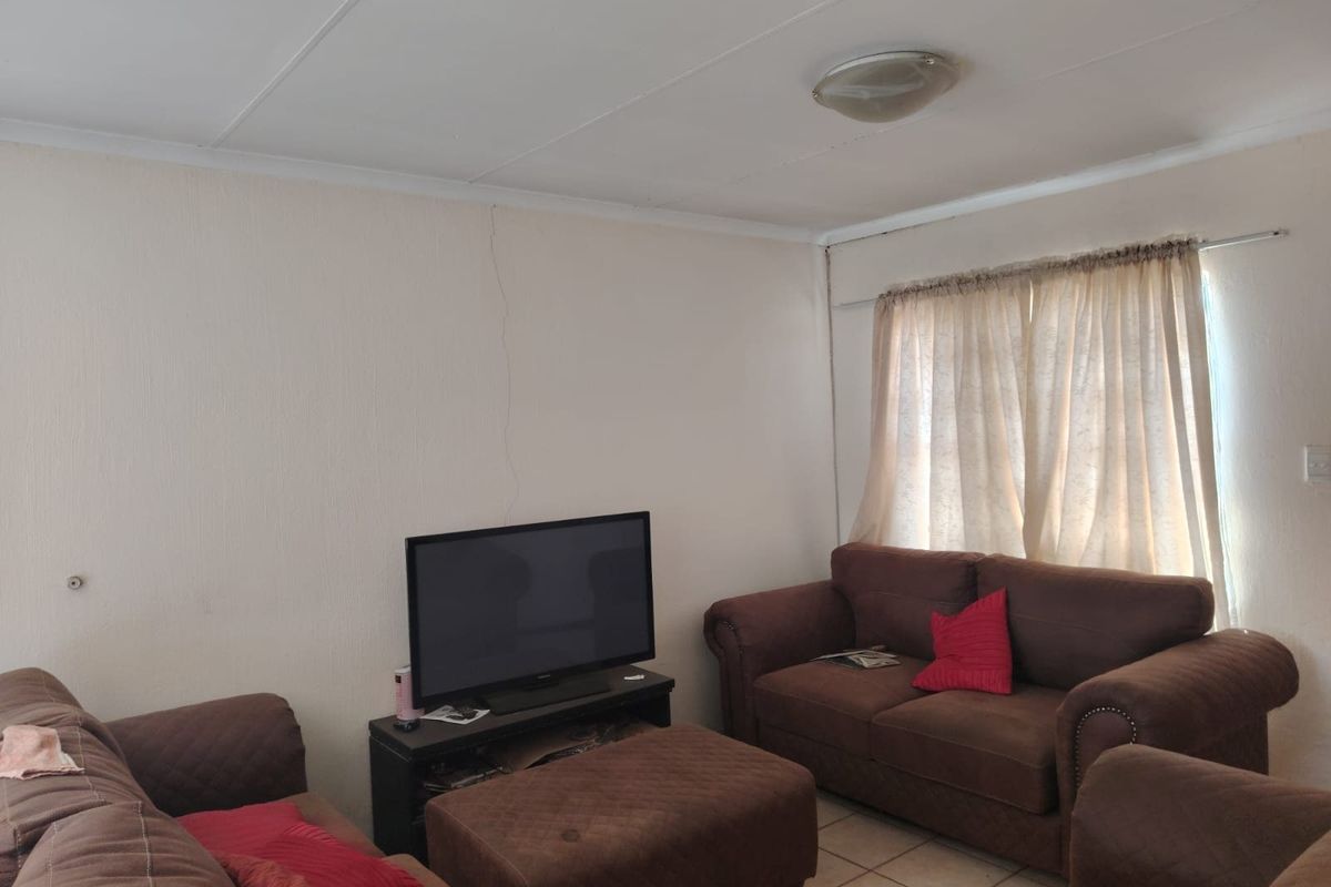 A living room featuring tiled flooring and a visible vertical wall crack, offering a functional space ready for cosmetic updates.
