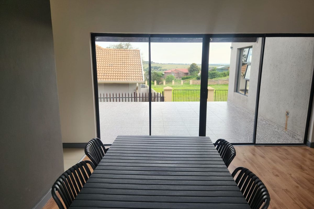 Living area featuring large sliding glass doors that open onto a tiled patio with views of the surrounding landscape.