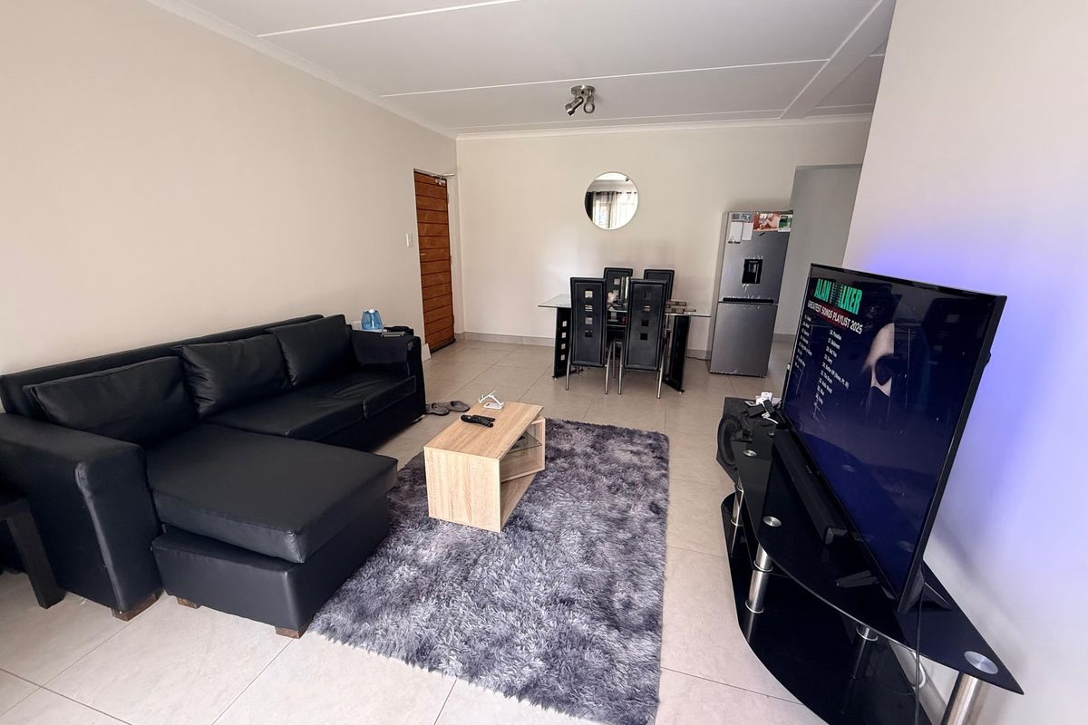 An open-plan living and dining area featuring neutral tiled flooring and a coved ceiling, providing a functional and versatile space for daily living.