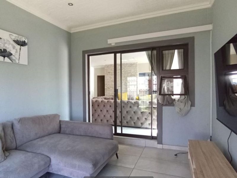 A well-maintained living room featuring tiled flooring, recessed lighting, and a sliding glass door providing access to an adjacent space.