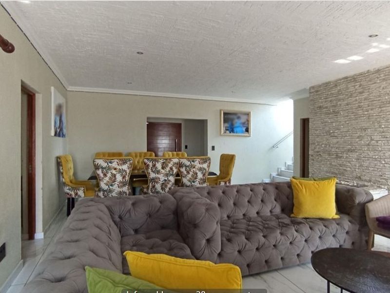 Spacious open-plan living and dining area featuring a textured stone accent wall, tiled flooring, and recessed lighting.