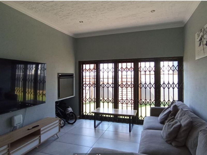 A comfortable living room featuring tiled floors, a built-in fireplace, and large sliding glass doors with security gates leading to the outdoor area.