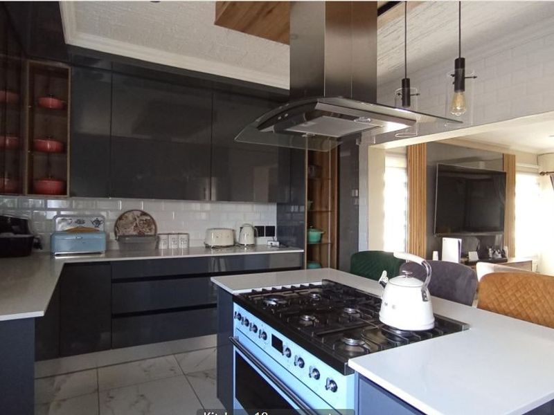 Modern open-plan kitchen featuring high-gloss cabinetry, quartz countertops, a central gas cooktop island, and stylish subway tile backsplash, seamlessly flowing into the living area.
