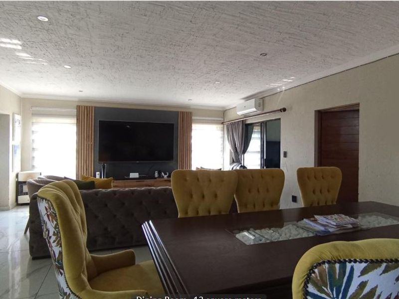 Spacious open-plan living and dining area featuring a stone accent wall, modern timber slat detailing, and tiled flooring throughout.