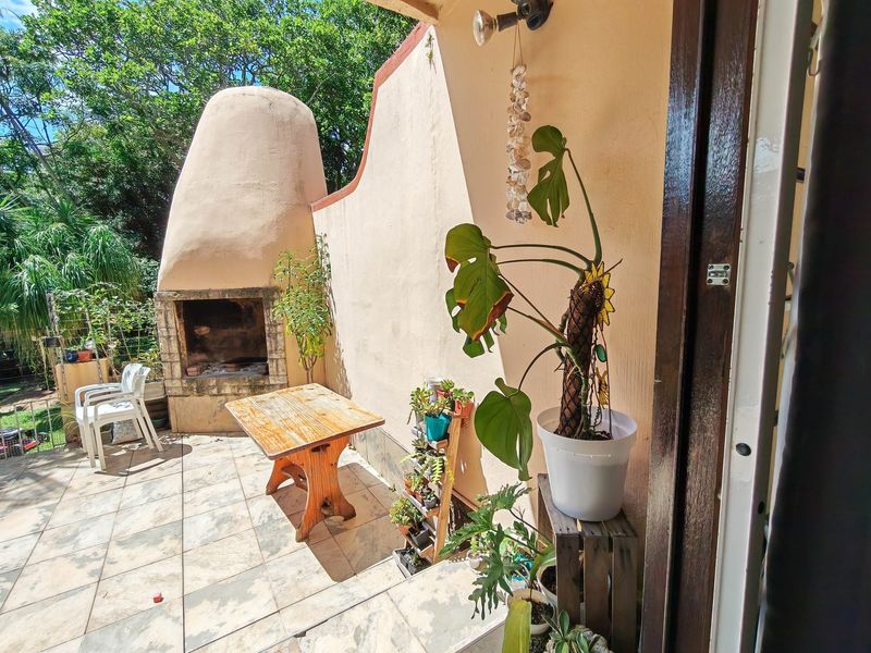 Outdoor patio area featuring a built-in fireplace and tiled flooring, providing a functional space for outdoor entertaining.